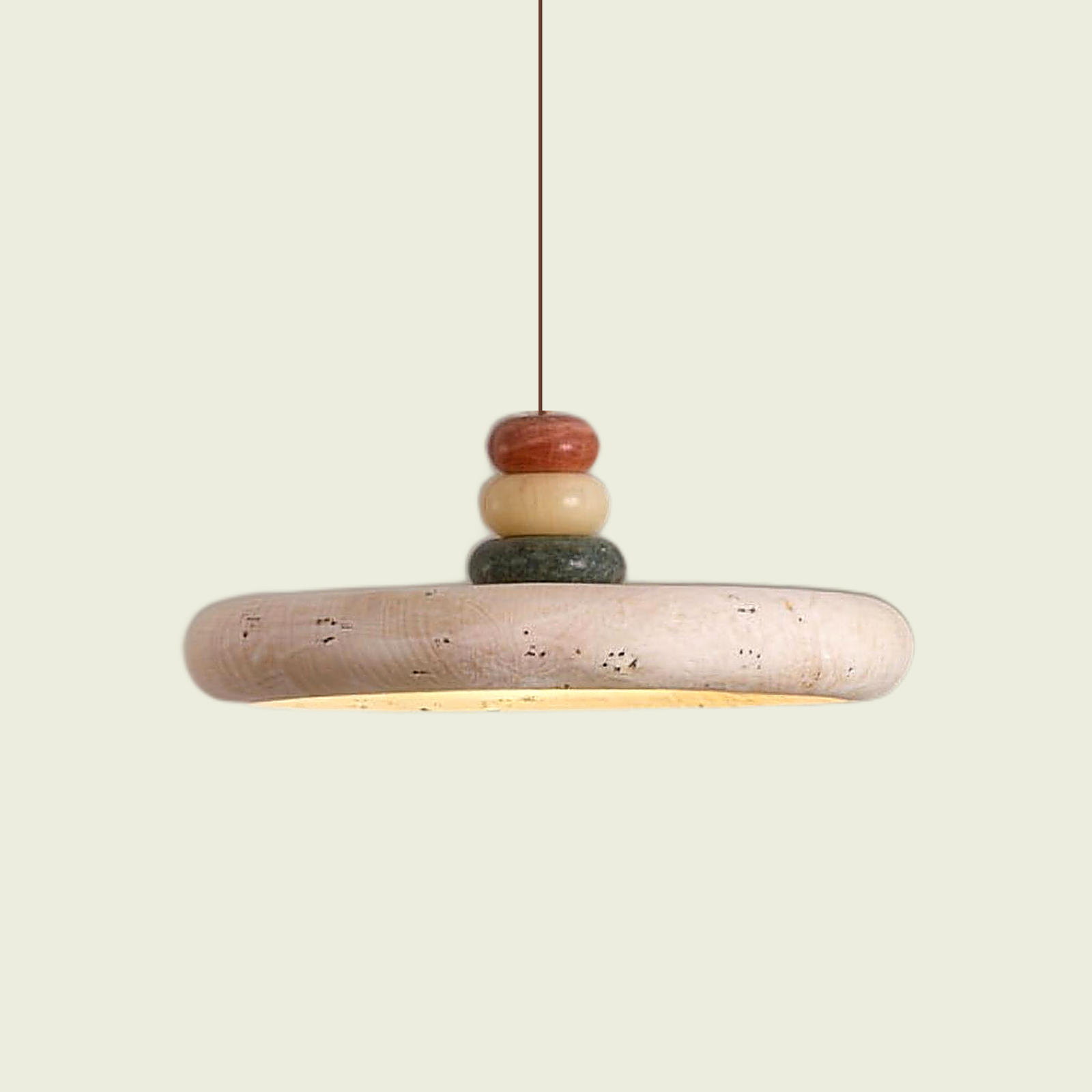 Travertine disc pendant light with stacked stone pebble finial and warm underglow, front view