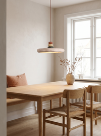 Travertine disc pendant lit above an oak dining table in a daylit Japandi dining room