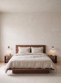 A pair of travertine wall sconces either side of a bed in a daylit bedroom