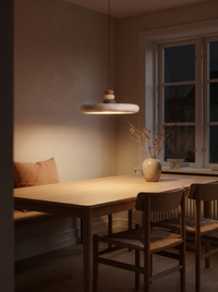 Travertine disc pendant glowing as the main light over a table in a dark room at night
