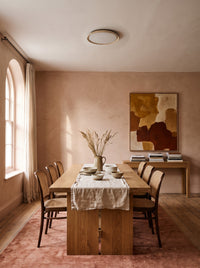 Travertine wabi-sabi ceiling light above a dining table in a daylit clay-pink dining room