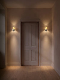 A pair of chrome pleated ceramic wall sconces as the only light in a dark hallway at night