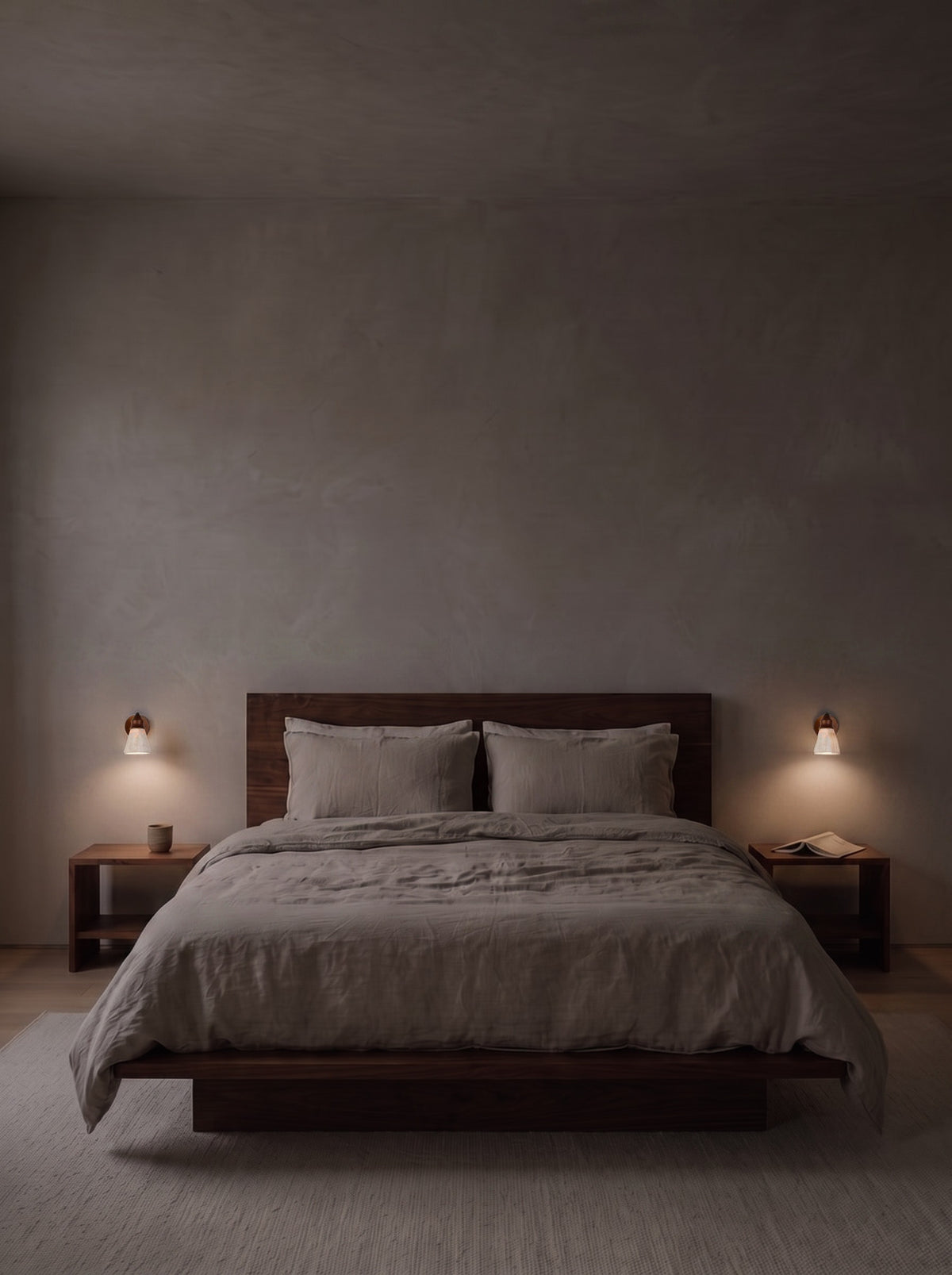 A pair of travertine wall sconces as the only light in a dark bedroom at night