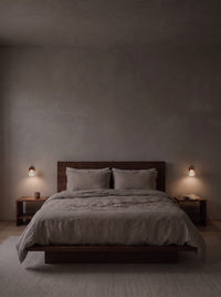 A pair of travertine wall sconces as the only light in a dark bedroom at night