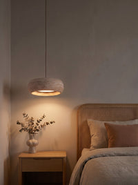 Travertine drum pendant as the warm main light above a nightstand in a dark bedroom at night