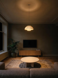 Woven dome pendant light as the only light over a coffee table in a dark living room at night
