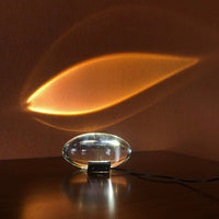 Crystal projection lamp on a wood desk casting a warm beam of light