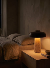 Travertine mushroom table lamp glowing warm at night on a nightstand
