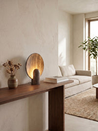 Travertine disc table lamp on a walnut console in a daytime living room