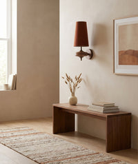 Red cloth cone wall sconce in a daylit hallway above a walnut bench