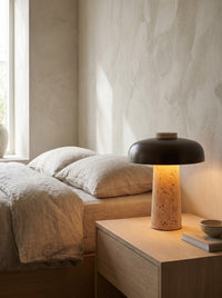 Travertine mushroom table lamp on a bedside nightstand in daylight