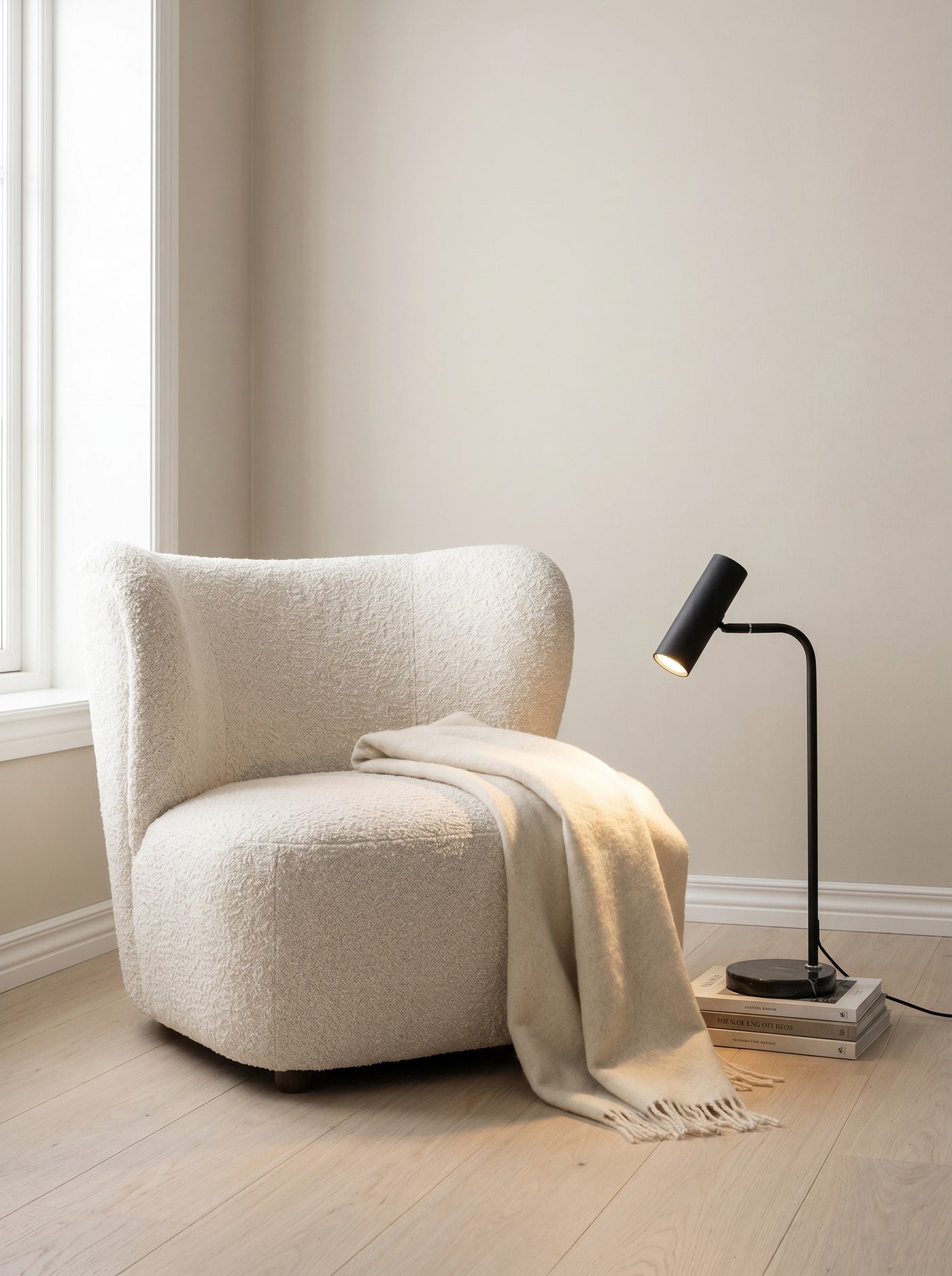 Black spotlight floor lamp beside a reading chair, daytime
