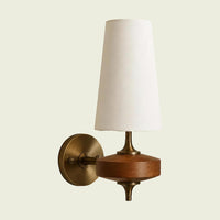 White fabric cone wall sconce on walnut mount with brass wall plate, angled
