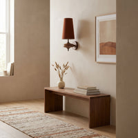 Red cloth cone wall sconce in a daylit hallway above a walnut bench