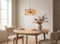 Amber glass pendant lit above an oak dining table in a warm daylit room