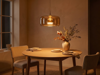 Amber glass pendant glowing over a dining table in a dark room at night