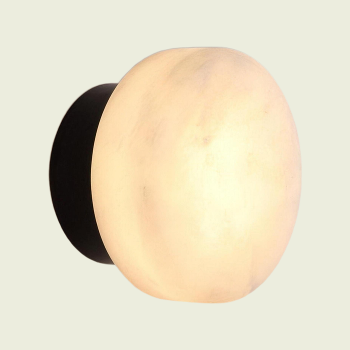 Marble dome wall sconce, cloud-stone shade on a black base, on a cream background